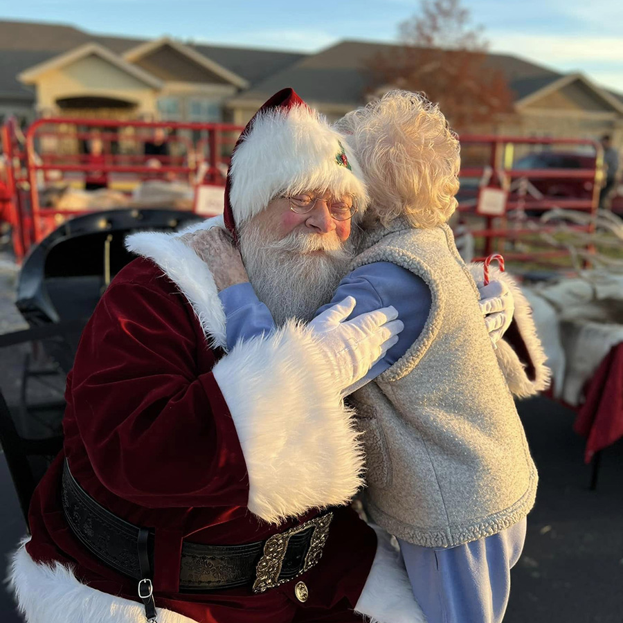 Witness Santa spreading love by hugging a Memory Care Resident during our tree lighting ceremony.