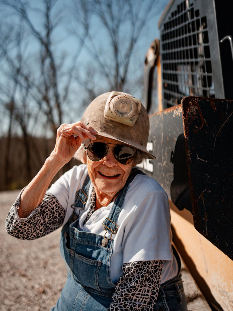 A heartwarming moment unfolds as Virginia, the centenarian, poses in overalls and a hard hat for her 100th Birthday photoshoot, embodying timeless beauty and wisdom.