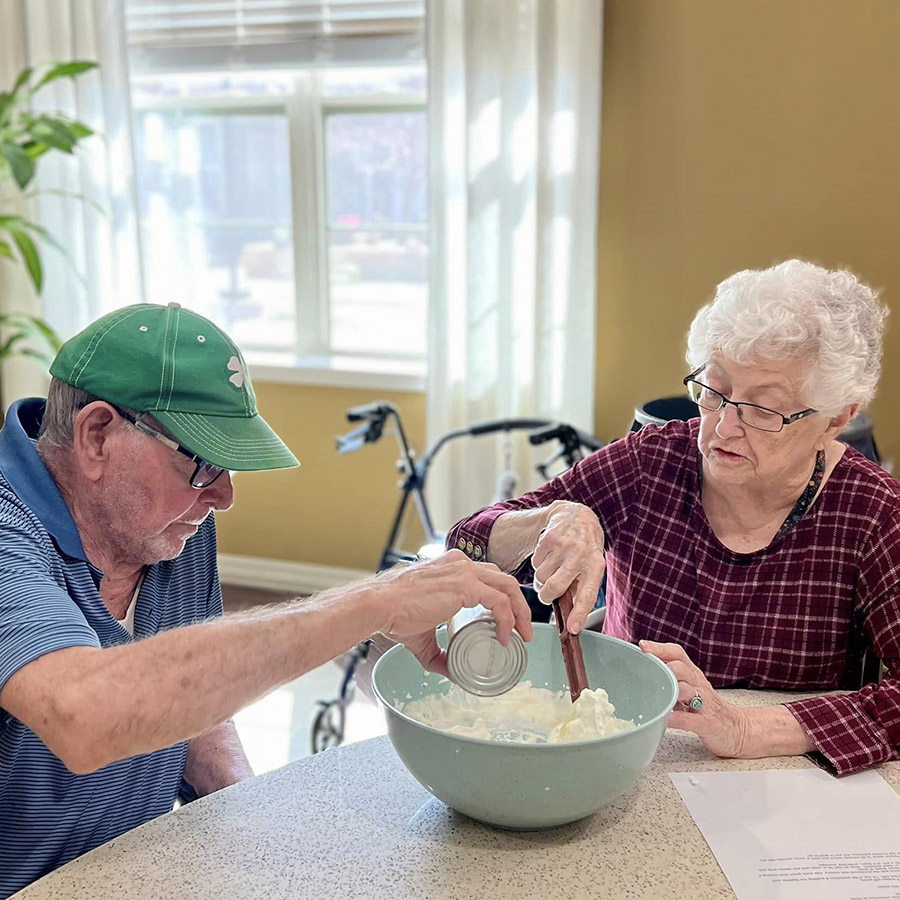 Elderly individuals in a senior living community preparing delicious homemade ice cream.