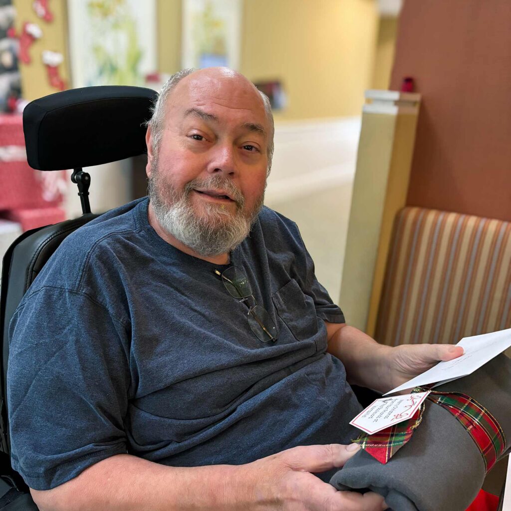 A senior resident at The Boulevard Senior Living of Wentzville smiles while holding a Christmas gift.