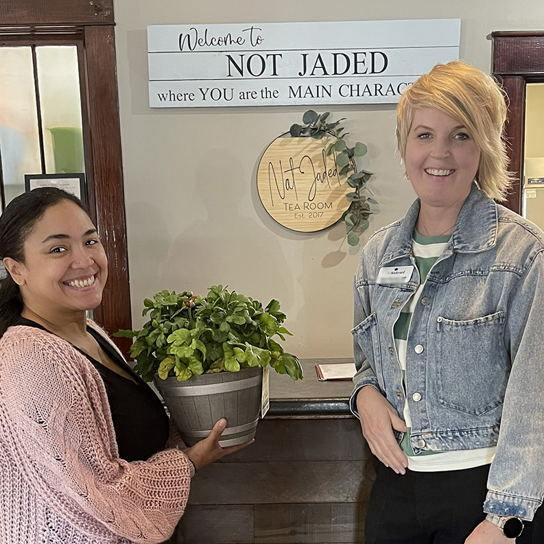 A Boulevard Wentzville team member presents a beautiful plant to a smiling owner of the Not Jaded Tea Room.