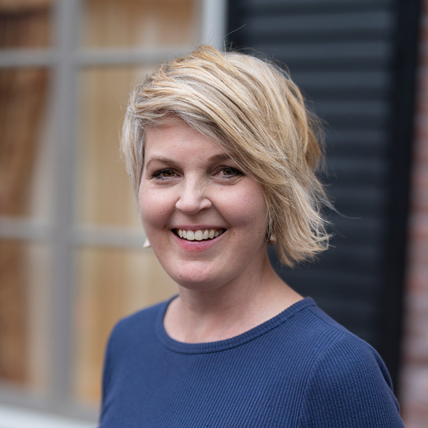 Krista Kruithoff, Memory Care Director at The Boulevard Senior Living of Wentzville, smiling in a professional headshot, wearing a blue top, with a softly blurred outdoor background featuring window and siding details.