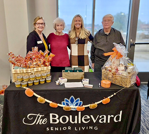 Residents and team members at The Boulevard Wentzville smile behind a display table during a community event.